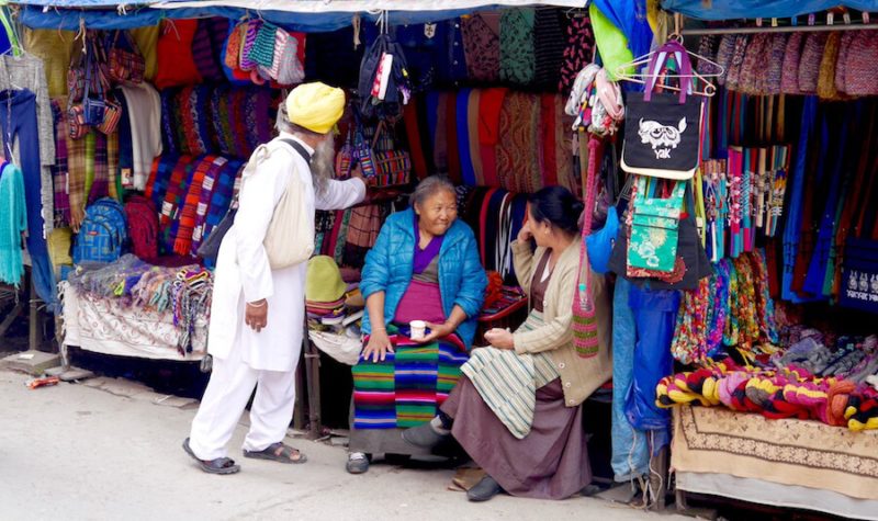 a Sikh Indian man buying souvenirs from Tibetan ladies in Jogiwara Road, McLeod Ganj, India